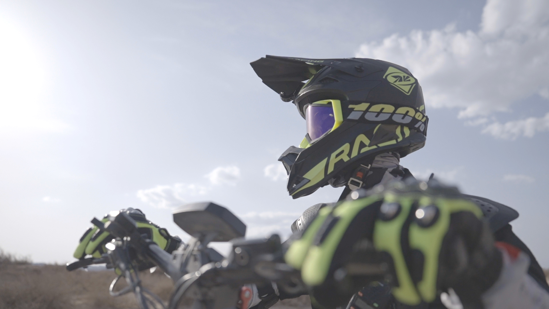 Rider wearing a black and green full-face helmet and gloves at the handlebars